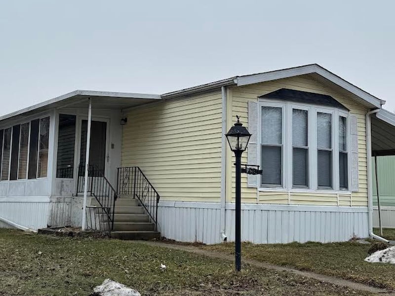 Street view of singlewide modular home with yellow siding.