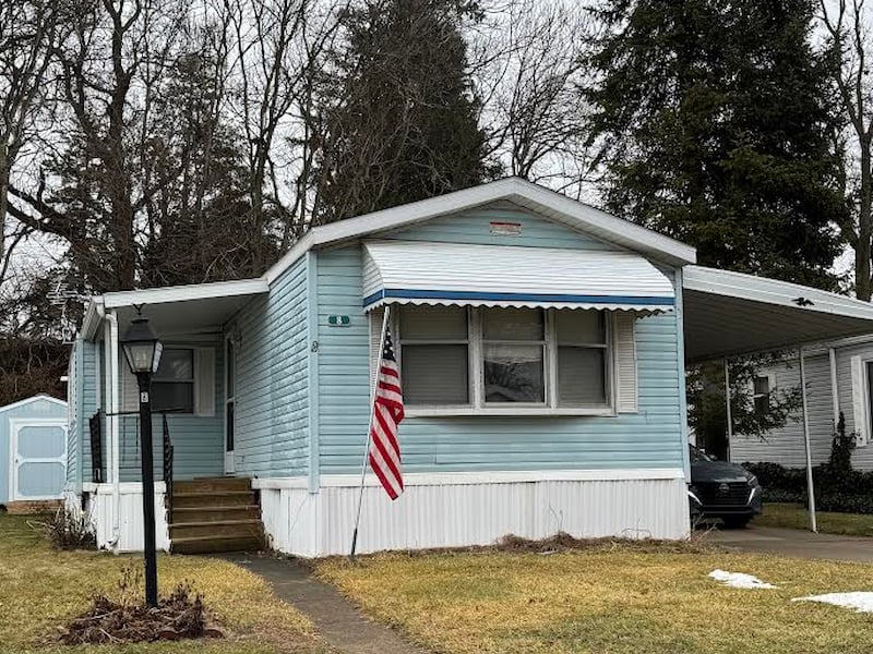 Street view of singlewide mobile home with blue siding.